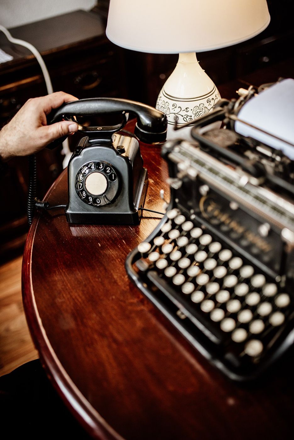 Vintage telephone and typewriter lit by a warm lamp